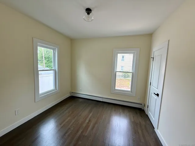 an empty room with wooden floor and window