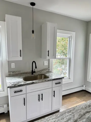 a kitchen with granite countertop white cabinets and a sink