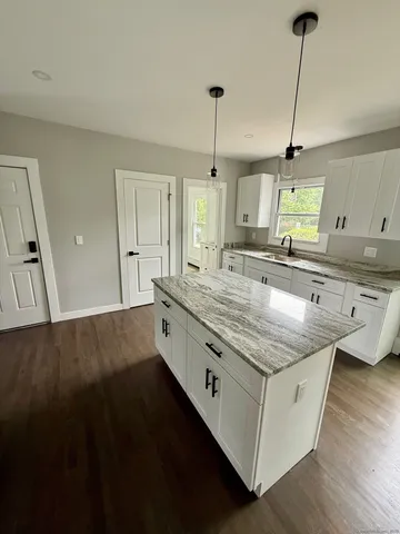 a kitchen with stainless steel appliances granite countertop a sink a stove and a wooden floor