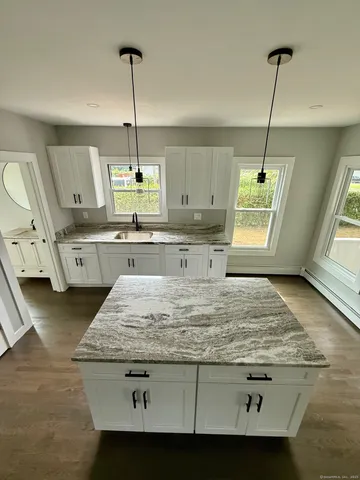 a kitchen with kitchen island granite countertop a sink a counter top space and cabinets