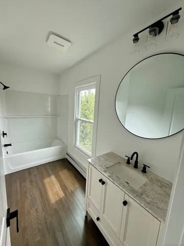 a bathroom with a granite countertop sink a mirror and shower