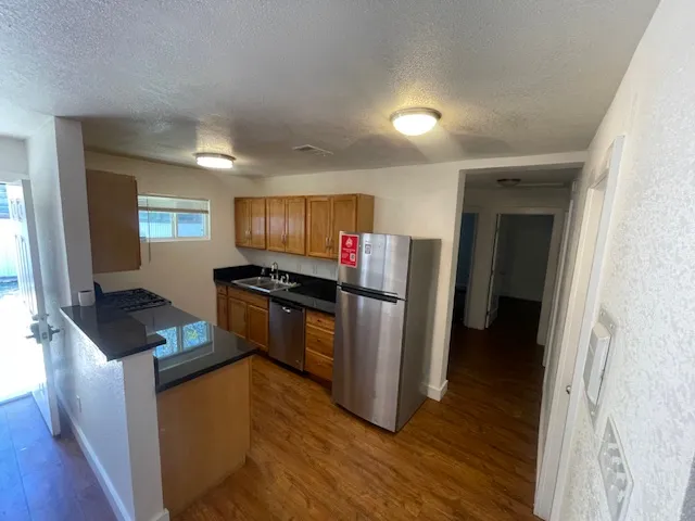a kitchen with granite countertop a refrigerator and a stove top oven