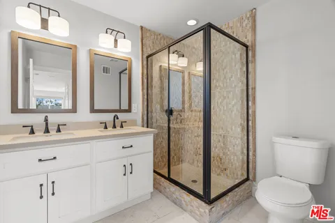 a bathroom with a shower sink mirror and toilet