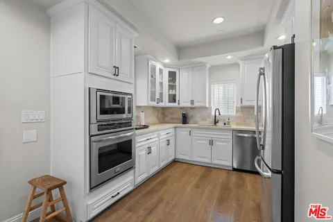 a kitchen with white cabinets and stainless steel appliances