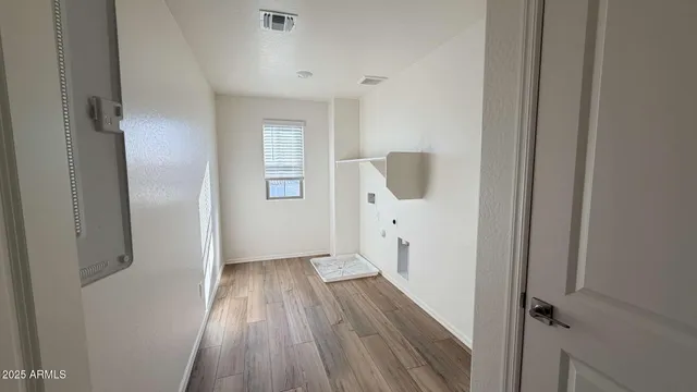 a view of a hallway with wooden floor and a bathroom