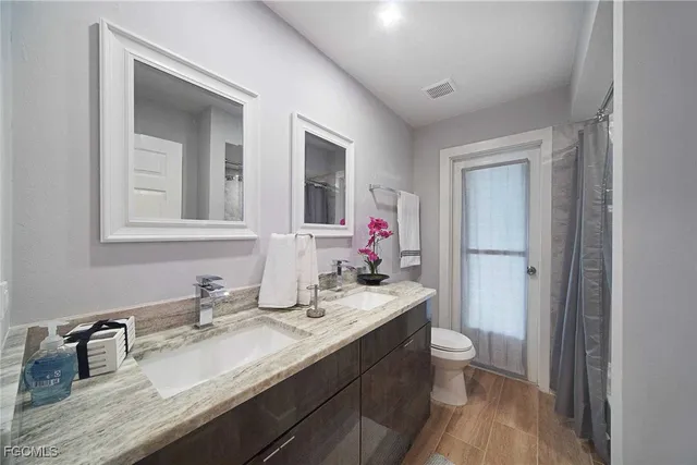 a bathroom with a granite countertop sink a toilet and a mirror