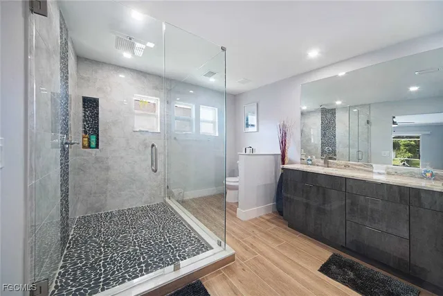 a bathroom with a sink a toilet a mirror and shower