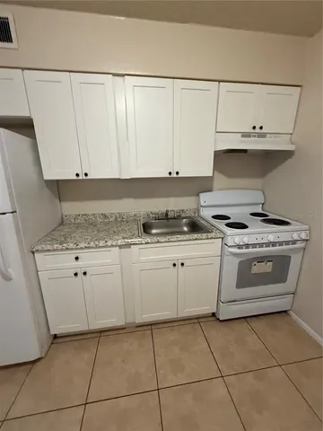 a kitchen with granite countertop white cabinets and white appliances