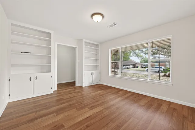 a view of an empty room with a window and wooden floor
