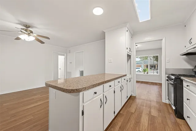 a kitchen with granite countertop a stove a sink and dishwasher with wooden floor