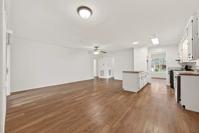 a view of kitchen and empty room with wooden floor