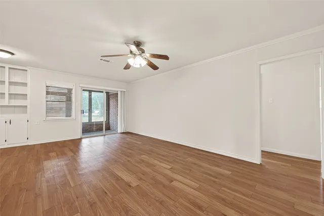 a view of empty room with wooden floor and fan