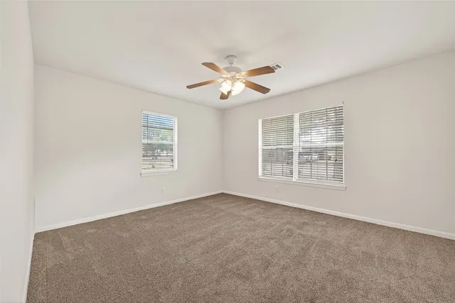 an empty room with a window and a ceiling fan