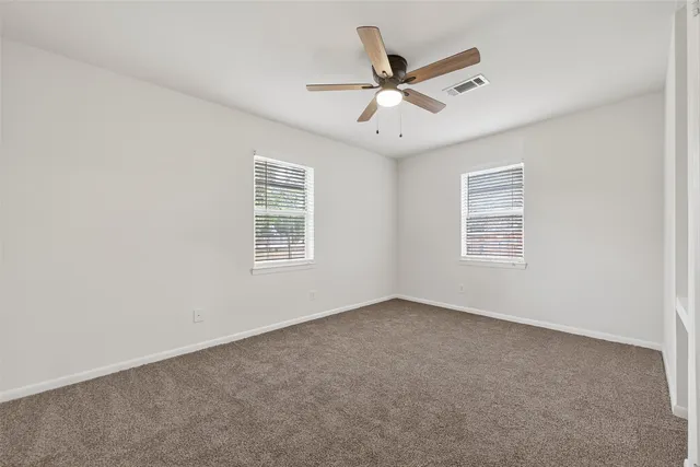 an empty room with windows and fan