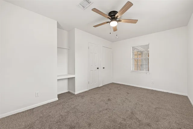 an empty room with a ceiling fan and window