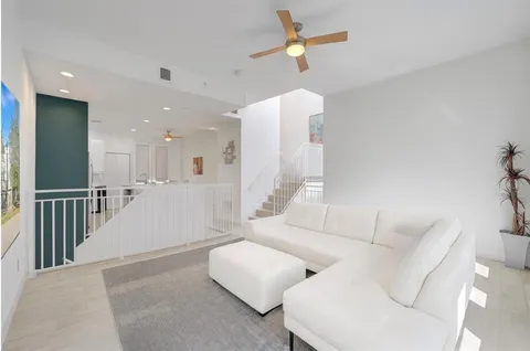 a living room with couches and kitchen view with wooden floor