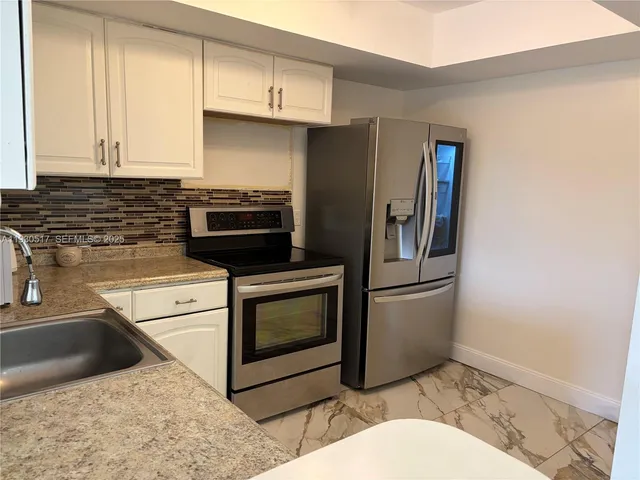 a kitchen with stainless steel appliances granite countertop a stove a refrigerator and a sink