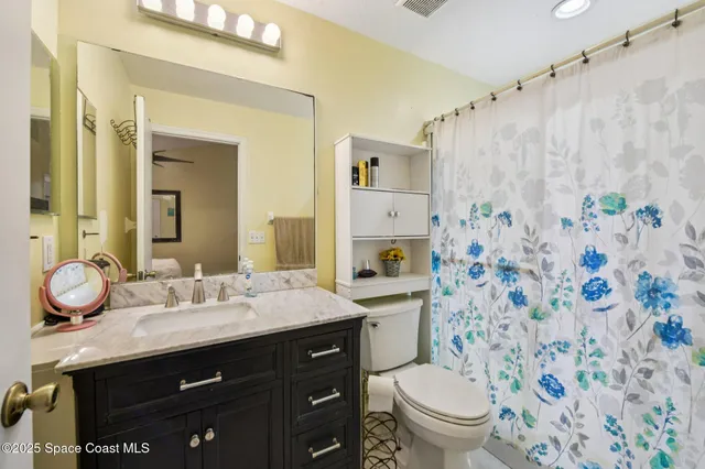 a bathroom with a granite countertop sink toilet mirror and shower