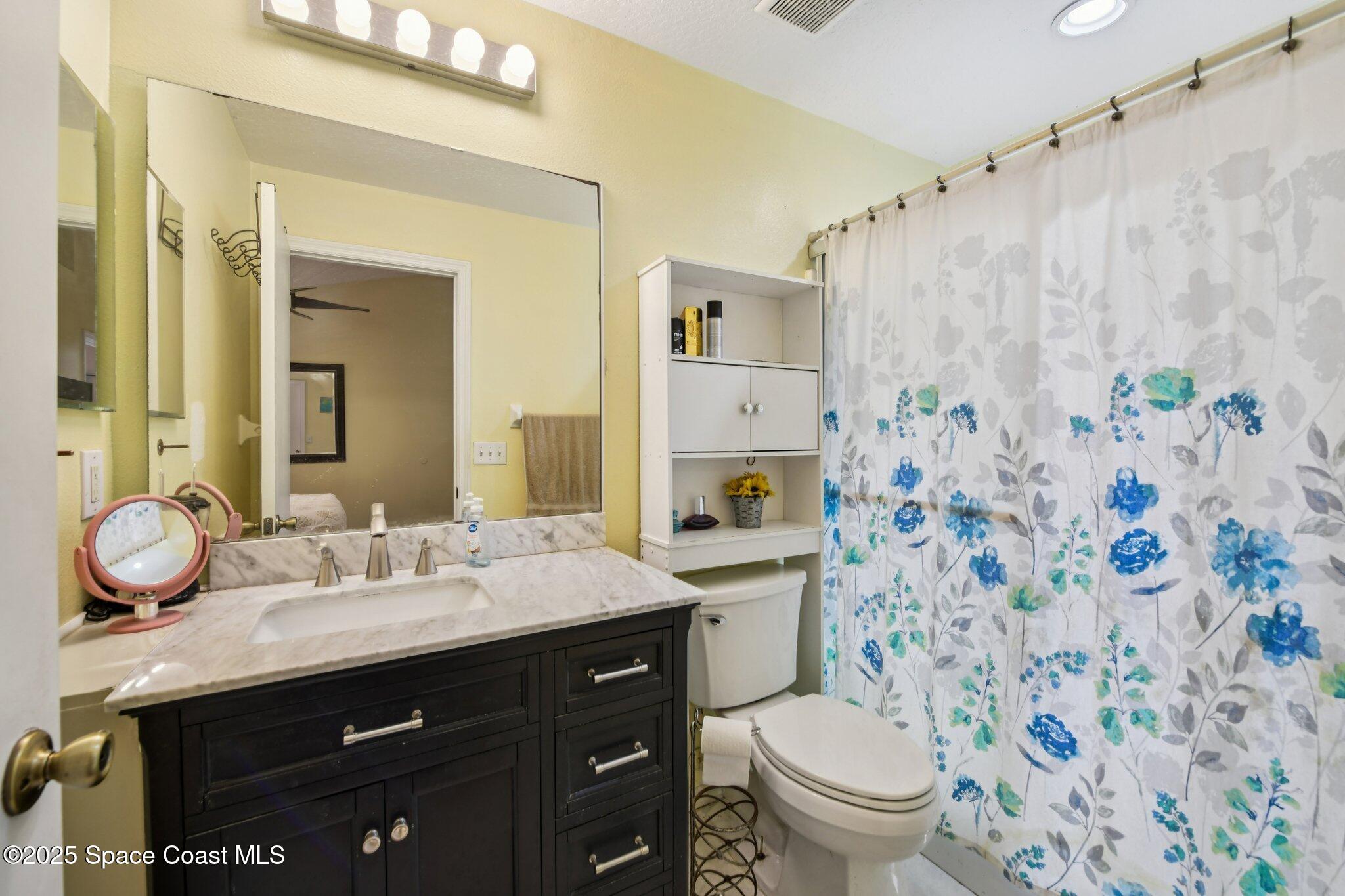 1125 Carey Glen Circle Orlando, FL 32824 - Photo 16 of 31 a bathroom with a granite countertop sink toilet mirror and shower