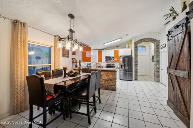 a dining hall with stainless steel appliances a dining table and chairs