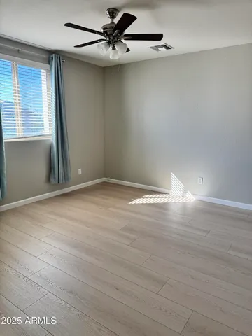 an empty room with wooden floor fan and windows
