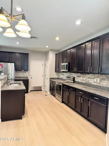 a large kitchen with stainless steel appliances wooden cabinets a stove and a refrigerator