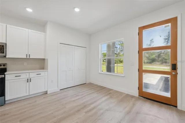 a view of an empty room with a window and a kitchen