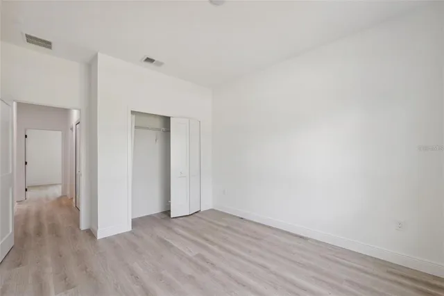 a view of an empty room with wooden floor and closet