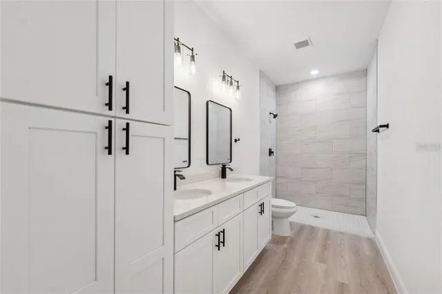 a bathroom with a double vanity sink toilet mirror and shower