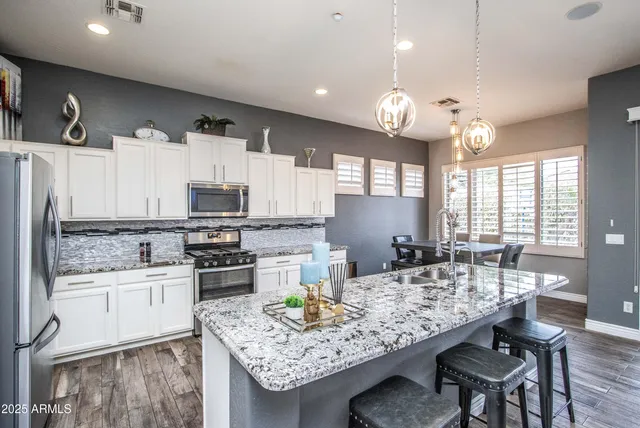 a kitchen with stainless steel appliances kitchen island granite countertop a table chairs and a refrigerator