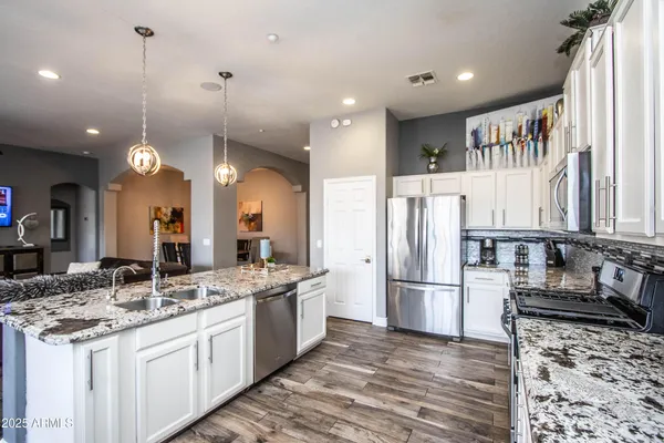a kitchen with stainless steel appliances granite countertop a sink refrigerator and cabinets