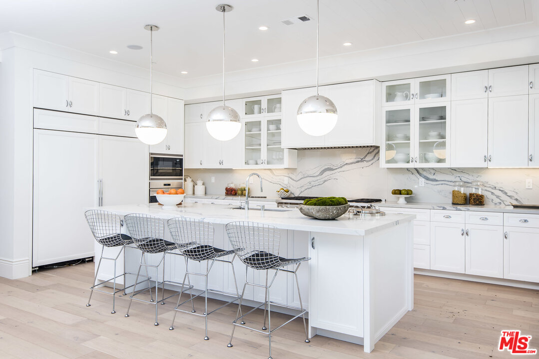 107 Larkin Place Santa Monica, CA 90402 - Photo 16 of 51 a kitchen with stainless steel appliances granite countertop a white refrigerator a sink dishwasher and white cabinets with wooden floor
