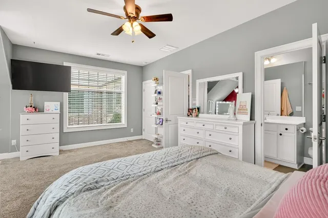 a bedroom with a large bed couch and windows