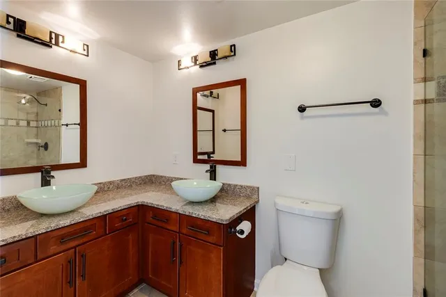 a bathroom with a granite countertop sink toilet and mirror