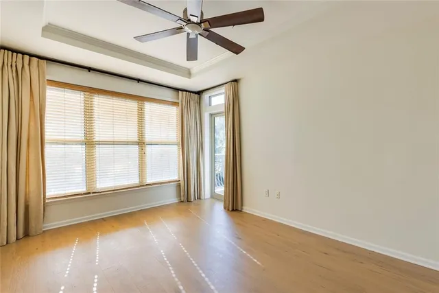 an empty room with wooden floor fan and windows