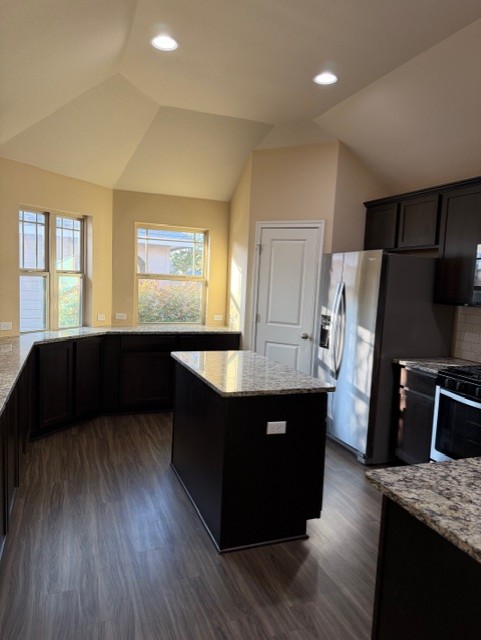 918 Silo Street San Marcos, TX 78666 - Photo 10 of 24 a kitchen with stainless steel appliances kitchen island granite countertop wooden cabinets a refrigerator a sink a stove a counter space and a window