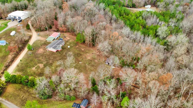 a view of a house with large trees and lawn chairs