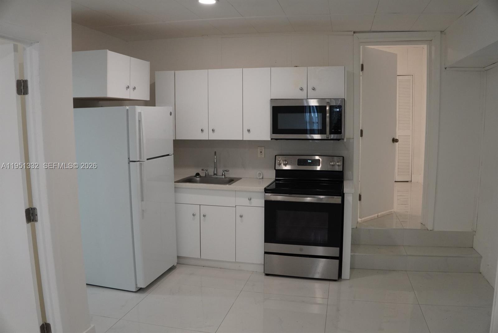 61 Southwest 58th Court, Unit D Miami, FL 33144 - Photo 2 of 7 a kitchen with white cabinets and stainless steel appliances
