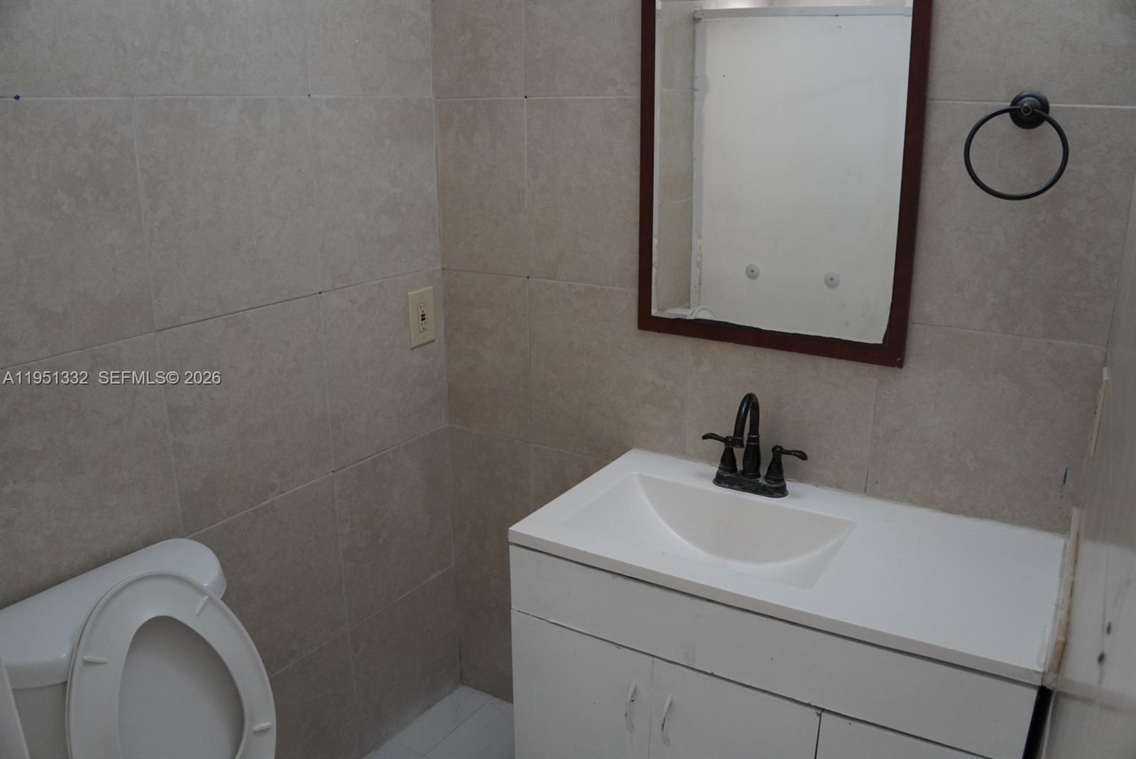 61 Southwest 58th Court, Unit D Miami, FL 33144 - Photo 4 of 7 a bathroom with a toilet sink vanity and mirror