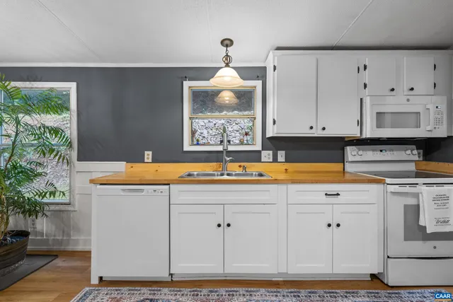 a kitchen with stainless steel appliances granite countertop a sink a stove and white cabinets