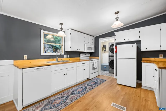 a kitchen with granite countertop a refrigerator a sink dishwasher and white cabinets with wooden floor