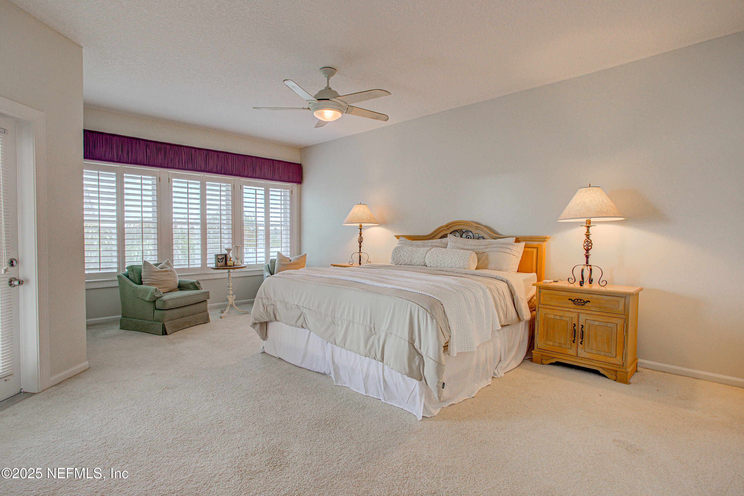 9155 June Lane St. Augustine, FL 32080 - Photo 29 of 43 a spacious bedroom with a bed and a chandelier