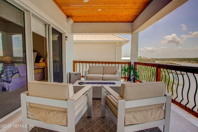 a view of a chairs and table on the wooden deck in front of a house