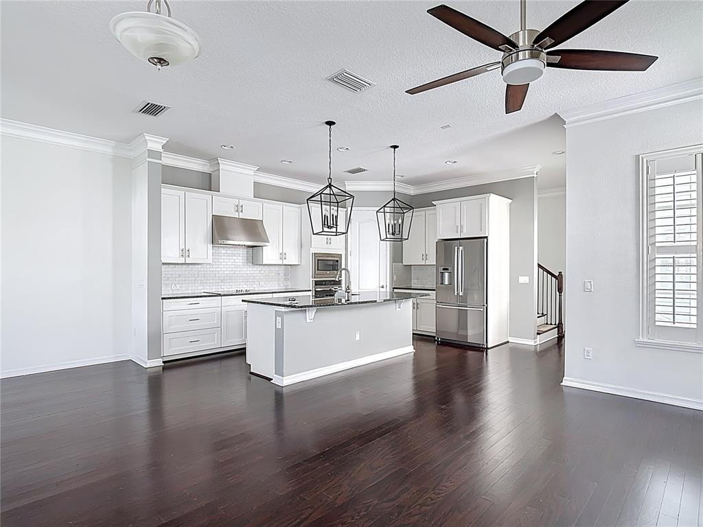 1513 Resolute Street Celebration, FL 34747 - Photo 9 of 43 a large kitchen with white cabinets stainless steel appliances and center island