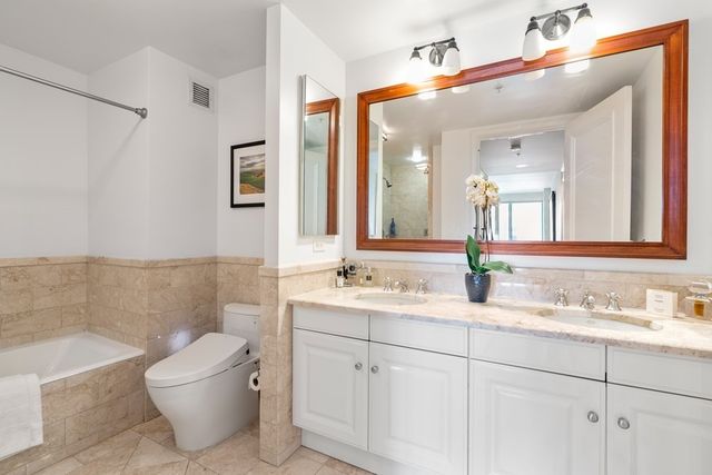 a bathroom with a granite countertop sink mirror and a bathtub