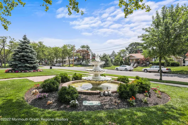 a view of a garden with water fountain and large trees
