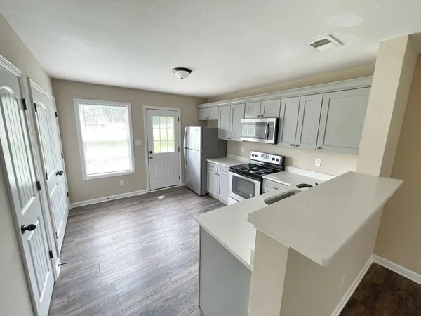 a kitchen with granite countertop a refrigerator stove and sink