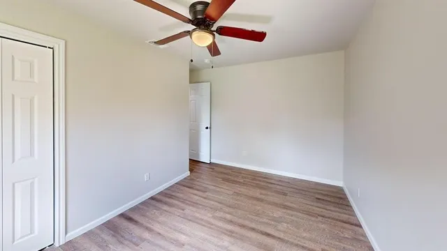 an empty room with wooden floor fan and white walls