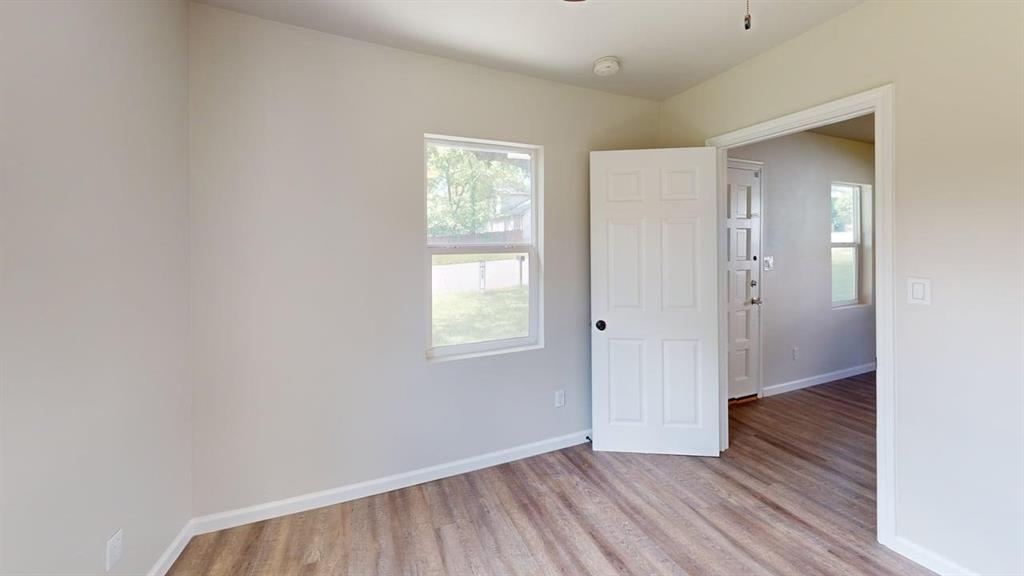 519 East Gandy Street Denison, TX 75021 - Photo 10 of 18 an empty room with wooden floor and windows
