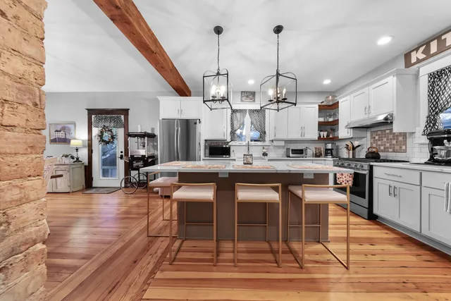a kitchen with stainless steel appliances kitchen island granite countertop a dining table chairs sink and cabinets